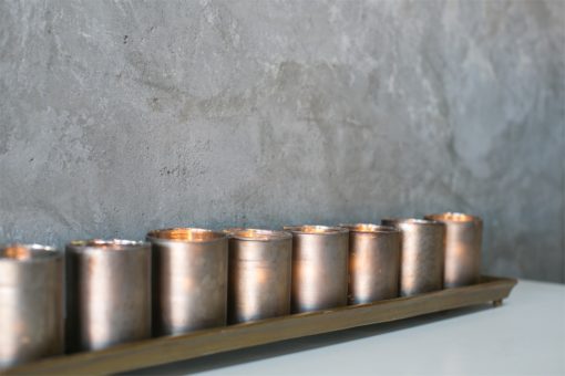 The Wilder Mercury Glass Candle Holder sits on an aluminum tray in two lengths and is available in a gold or silver finish. The Wilder Candle Holder Tray and Mercury Votive Set comes as a set of 5 Mercury Glass Candle Holders and sits on a 20" tray and the 34" tray holds 9 Mercury Votive Holders. Use the Wilder Mercury Glass Candle Holders spread throughout a room for subtle sparkle in your space. Line the Mercury Votives on the tray and use in uniform multiples on a dining table. The Wilder Aluminum Tray and Mercury Votives look amazing lining a mantle or cocktail table and each tray has an inset for each votive. Available in sets of multiples, the candle light options are endless for these classic Aluminum Candle Trays and Mercury Glass Votives.